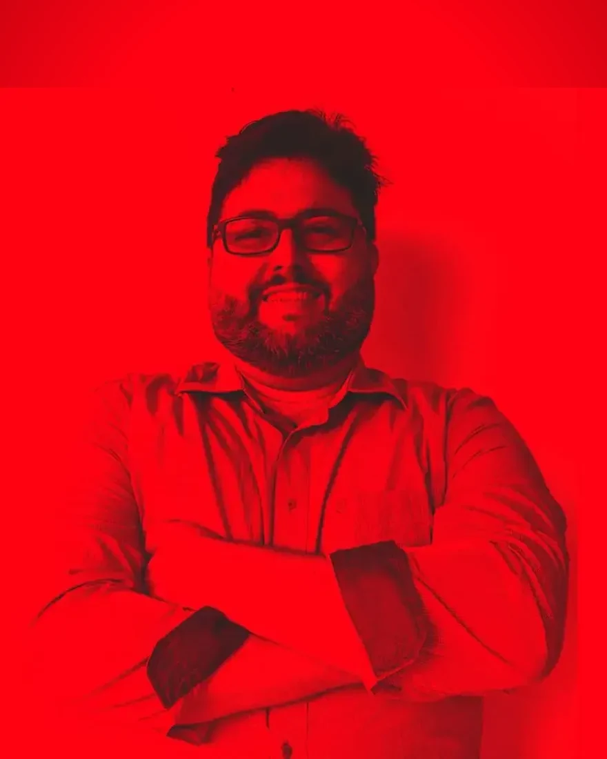Wilson Costa de braços cruzados, sorrindo, em retrato duotone vermelho